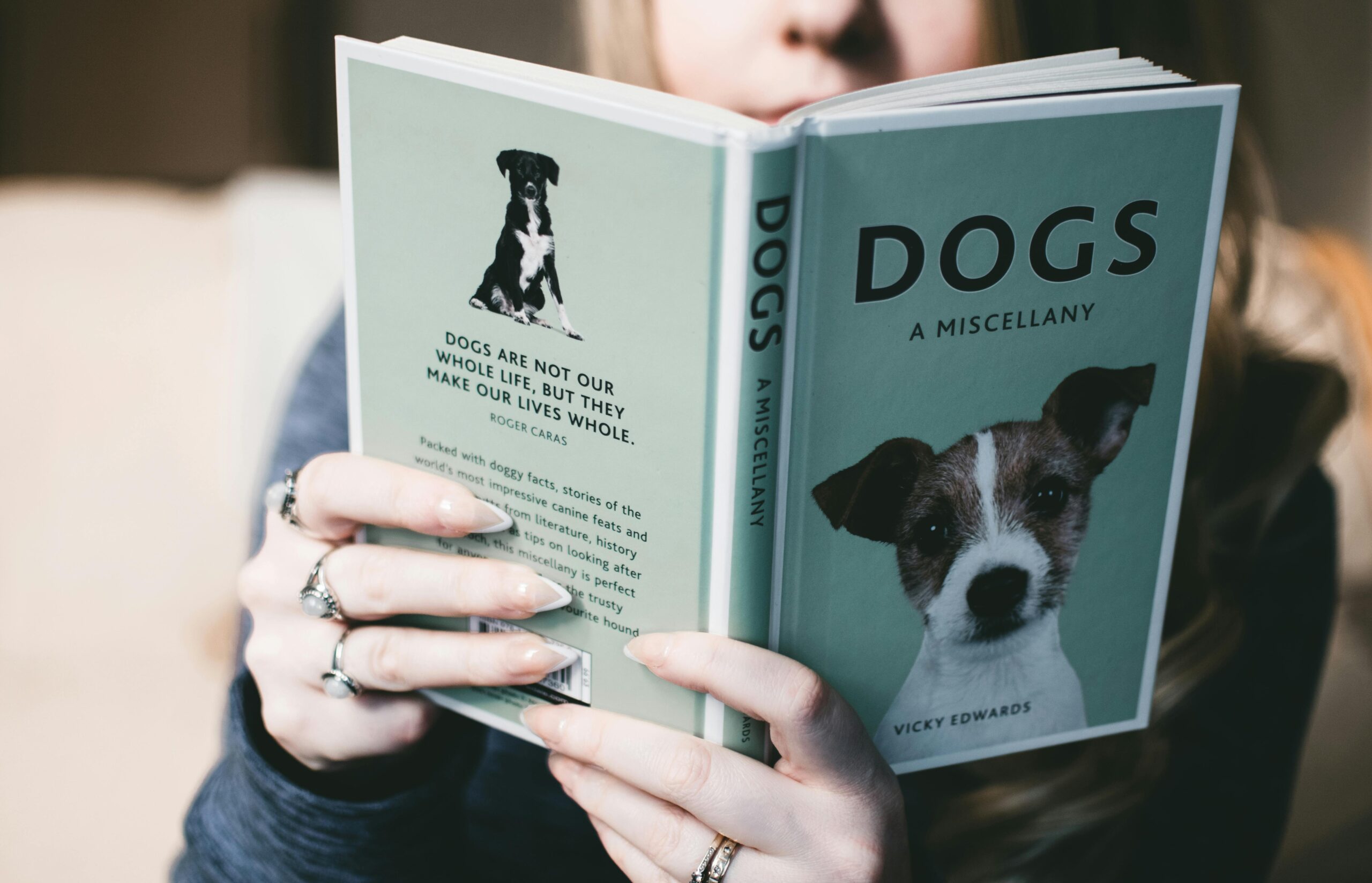 pexels-photo-880720-880720 Close-up of a person holding and reading a book about dogs, indoors.